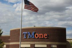 TMone Logo Blue and Orange on Brick Building in Spearfish South Dakota American Flag in front of building